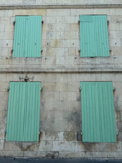 Image of a historic stone building featuring green shutters in Pons, Nouvelle-Aquitaine, France.