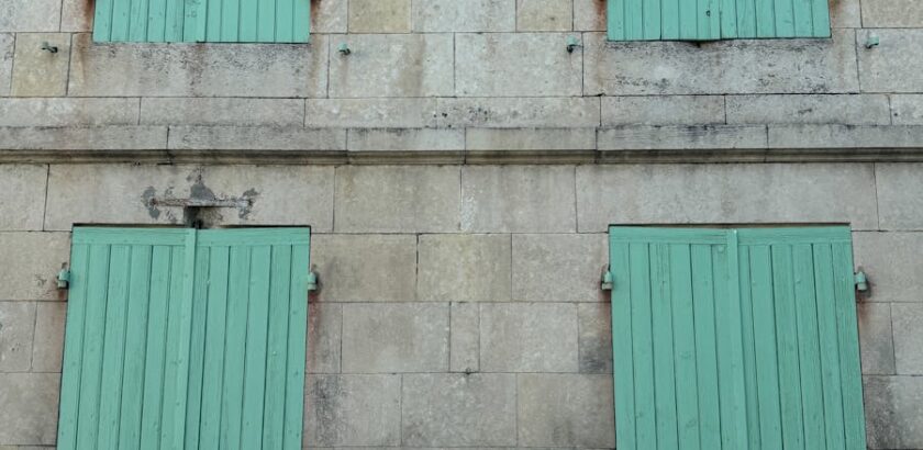 Image of a historic stone building featuring green shutters in Pons, Nouvelle-Aquitaine, France.